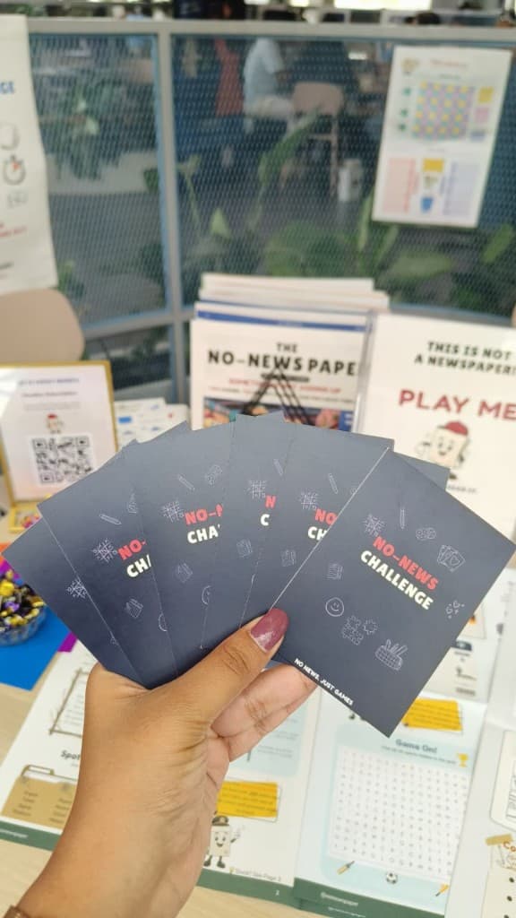 Hand holding No-News Challenge cards at a play table