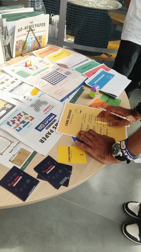 Hands solving Code Cracker and games from The No-News Paper